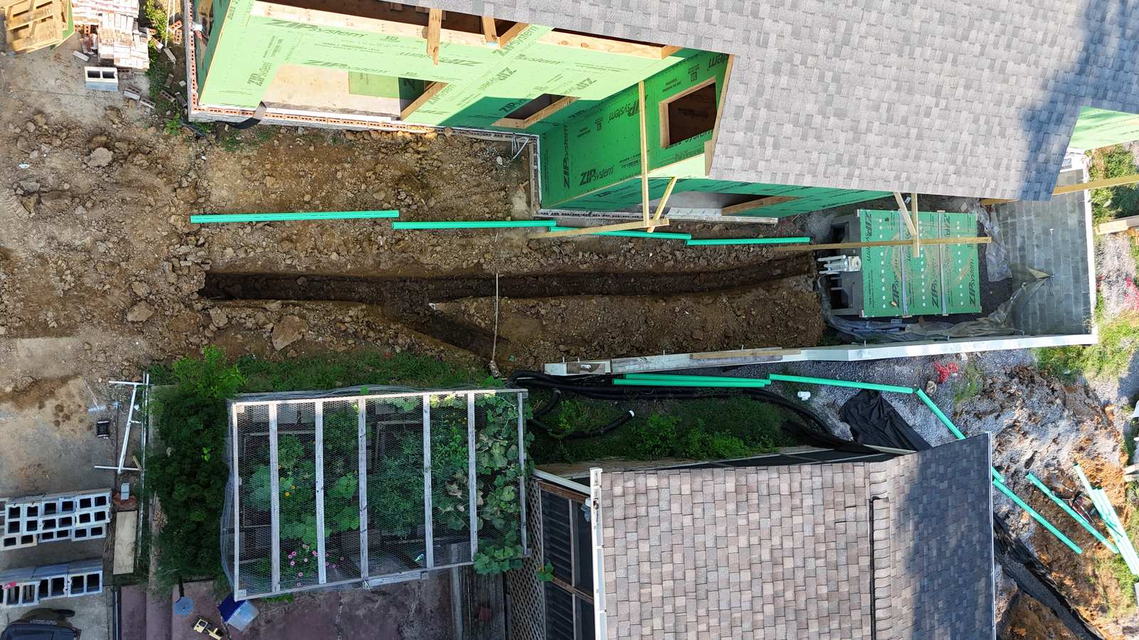 Aerial trench between two houses during drainage work.